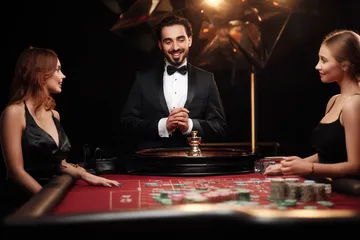 GOOD11111 Live Casino — Join thrilling real-dealer tables A professional dealer in a tuxedo greeting players at the roulette table, symbolizing the authentic live casino feel at GOOD11111.